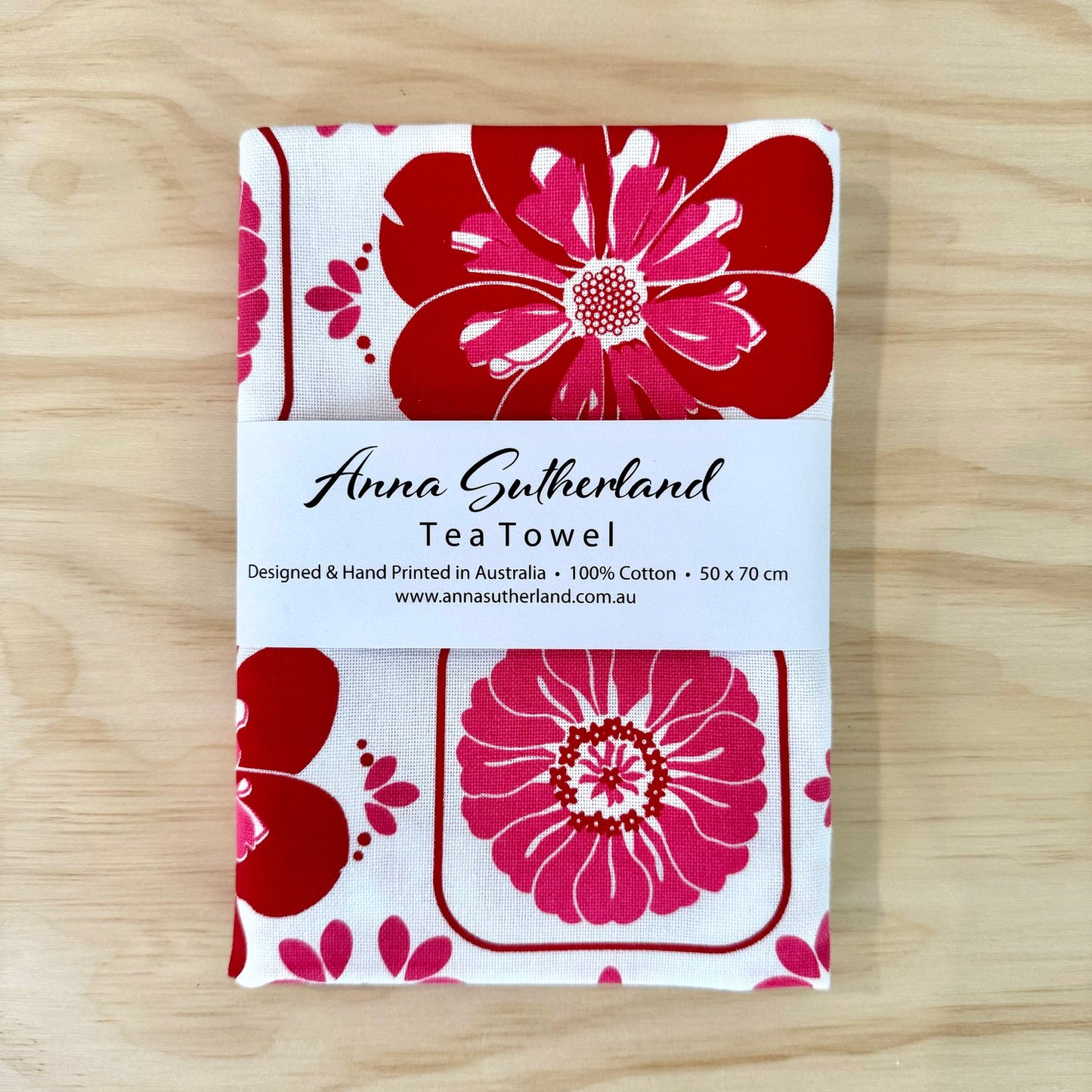 Tea towel with red floral design on a wooden surface