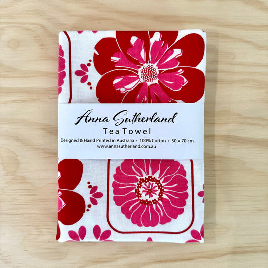 Tea towel with red floral design on a wooden surface
